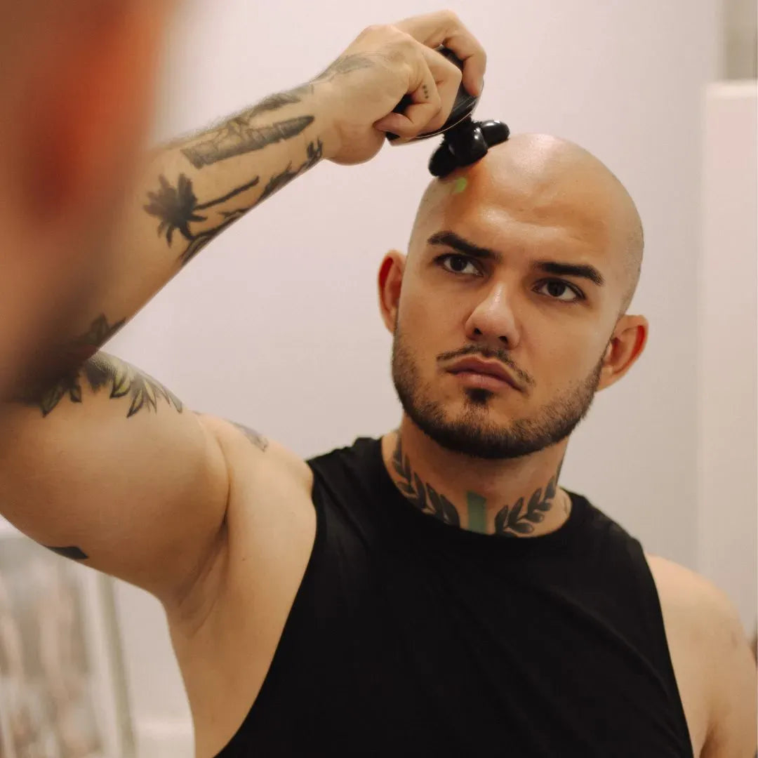 
Férfi a fejét borotválja Altino Trimora elektromos borotvával a fürdőszobai tükör előtt.
